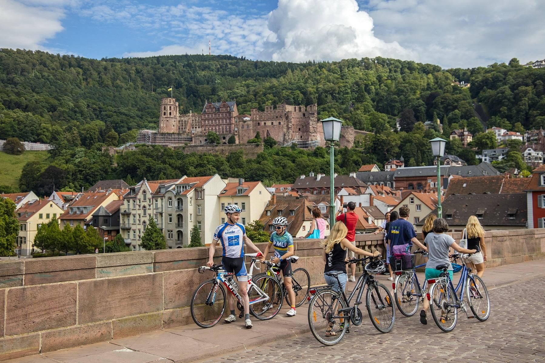 Schloss Heidelberg, Radfahrer auf der Alten Brücke mit Schloss im Hintergrund